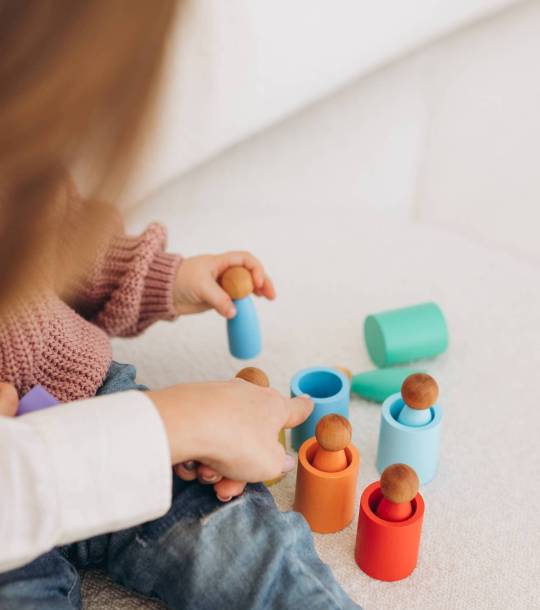 Cute little toddler girl playing at home with eco wooden toys. Happy child cutting vegetables and fruits with toy knife. The child playing educational games.